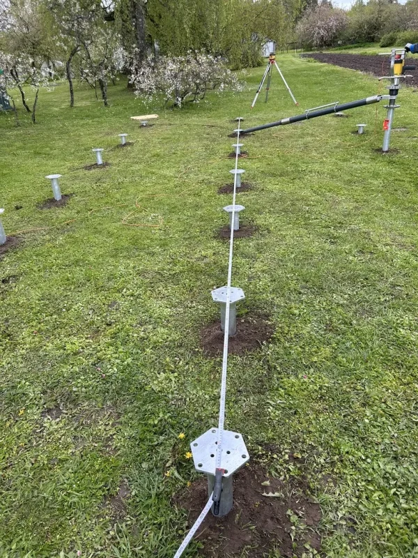 Screw pile installation in progress at Holiday home site in Cēsis Municipality with surveying tripod and laser level