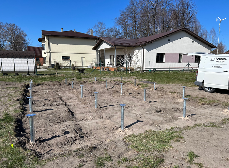 Screw piles driven into the sandy ground near a private home in Trīsciems using an LP Projekti van