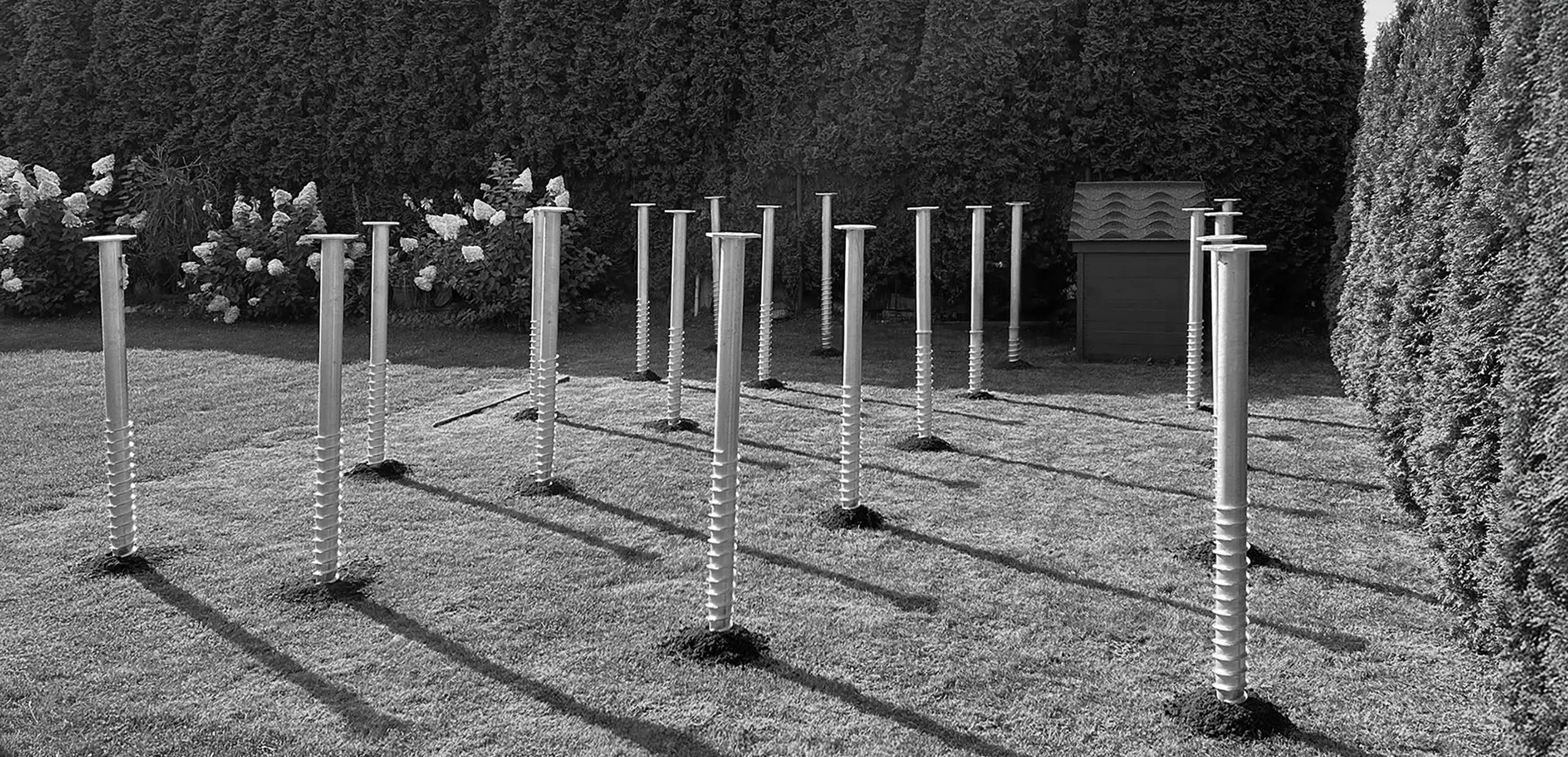 Screw piles driven into the ground in rows on the lawn to form the foundation of the structure